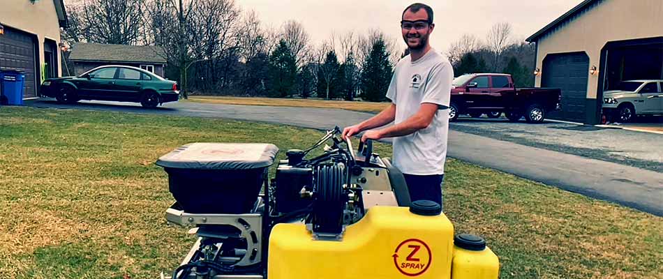 Fresh Cuts Lawn & Maintenance owner Austin using fertilization equipment near Fogelsville, Pennsylvania.